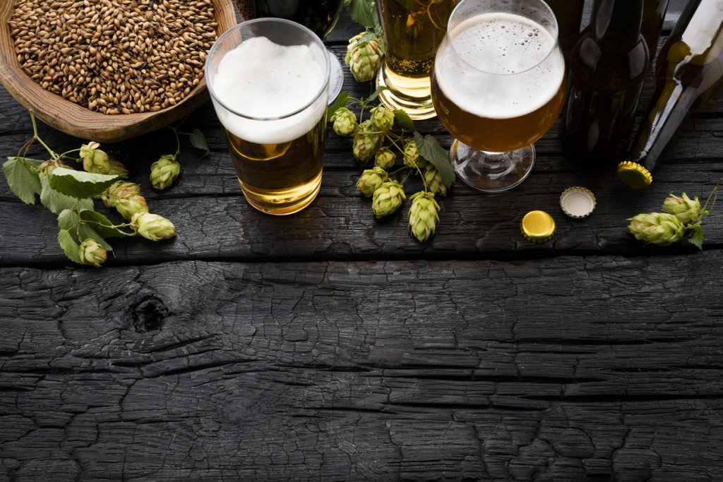 Beer glasses on a table, surrounded by decorative greens and a bowl of something to munch on