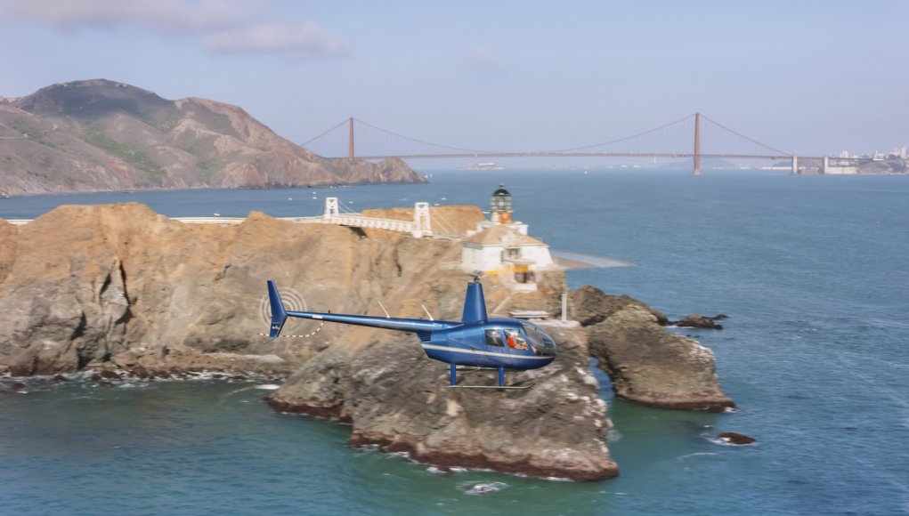 Aerial view of a helicopter flying past the Point Bonita Lighthouse at the entrance into the San Francisco Bay on a sunny day, California, USA.