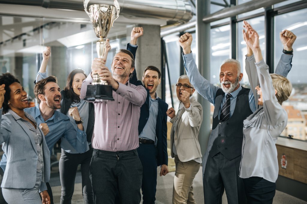 Large group of cheerful business people celebrating success with a trophy in the office.