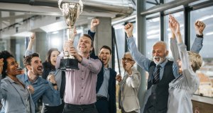 Large group of cheerful business people celebrating success with a trophy in the office.