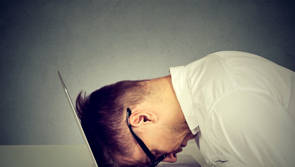 Desperate employee stressed man resting head on laptop