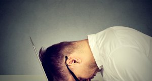 Desperate employee stressed man resting head on laptop