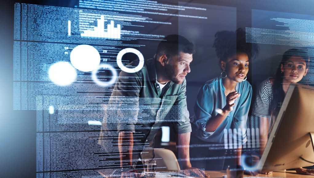 Shot of a group of programmers working together on a computer code at night