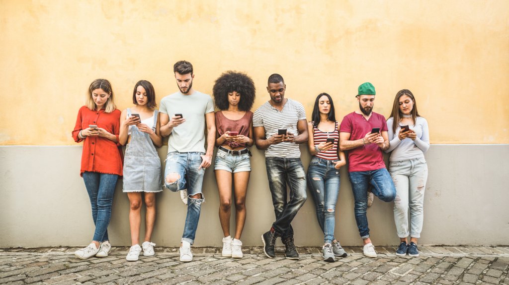 Multiracial friends using smartphone against wall at university college backyard - Young people addicted by mobile smart phone - Technology concept with always connected millennials - Filter image