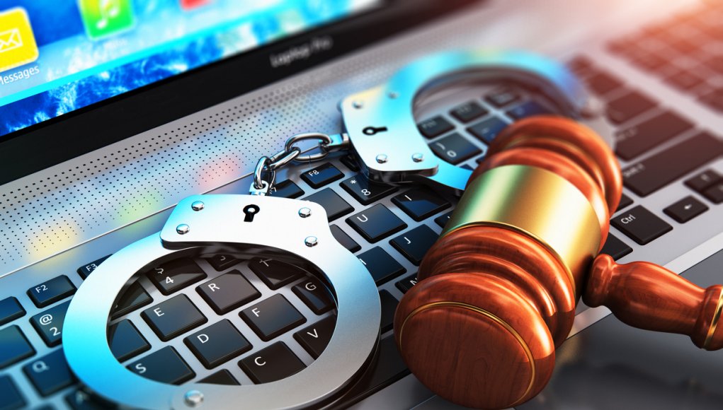 Creative abstract cyber crime, online piracy and internet web hacking concept: 3D render illustration of the macro view of metal handcuffs and wooden judge mallet, gavel or hammer on laptop notebook computer keyboard with selective focus effect
