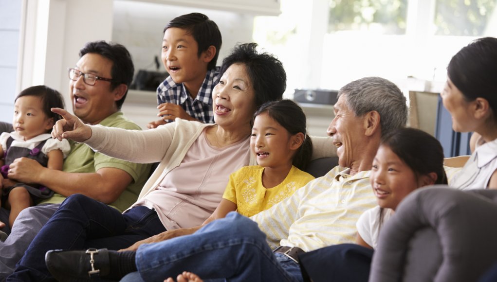 Extended Family Group At Home Watching TV Together