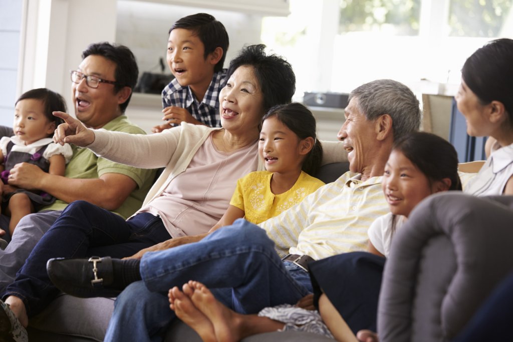 Extended Family Group At Home Watching TV Together