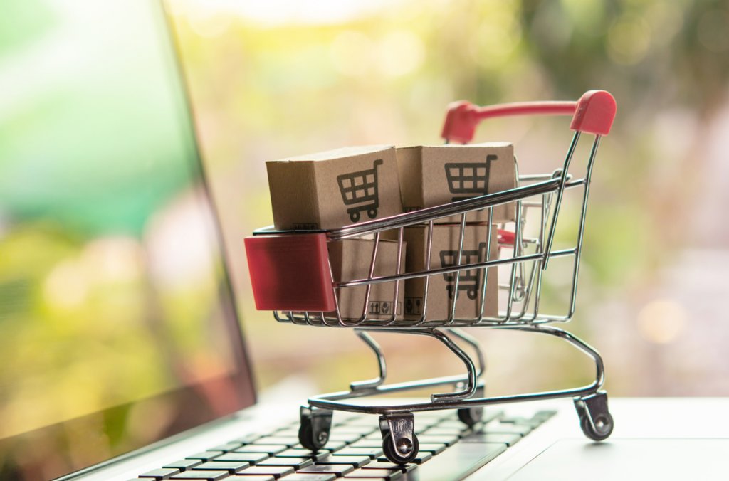 Shopping online concept - Parcel or Paper cartons with a shopping cart logo in a trolley on a laptop keyboard. Shopping service on the online web.