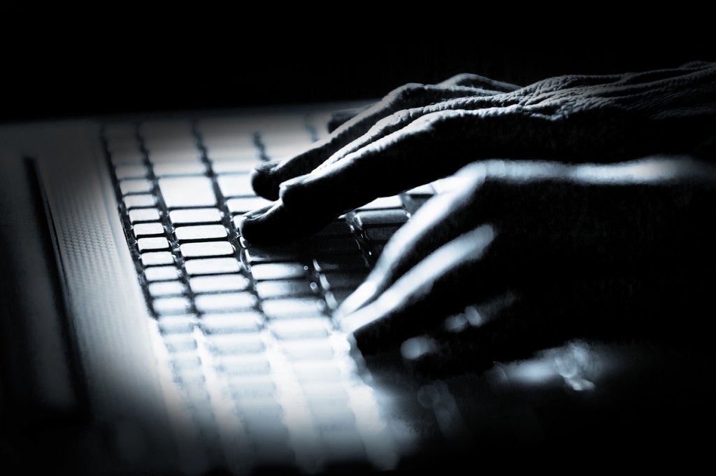 Hacker! Concept photo in high contrast black and white of hacker's fingers on keyboard