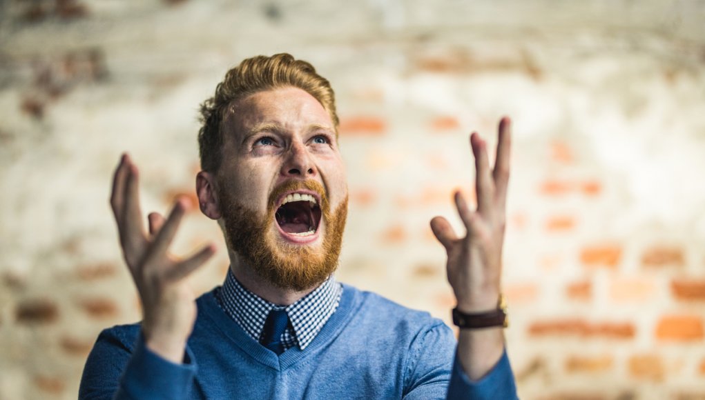 Young redhead businessman shouting from frustration.