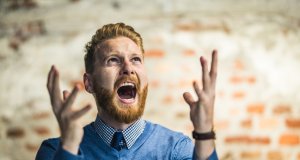 Young redhead businessman shouting from frustration.