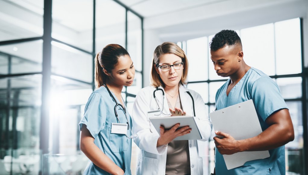 Hospital doctor and nurses examine something on a tablet, technology