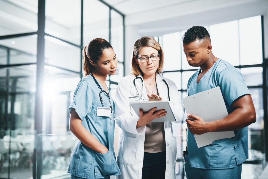 Hospital doctor and nurses examine something on a tablet, technology