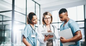 Hospital doctor and nurses examine something on a tablet, technology