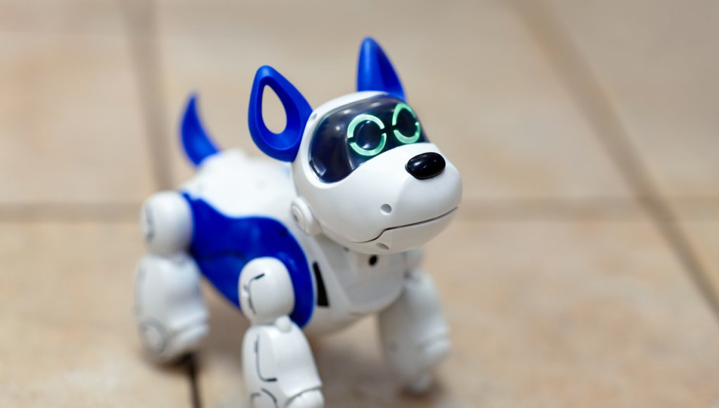 Electronic interactive toy dog puppy on a beige ceramic floor background of selective focus. High technology concept, pet of the future, electronic home.