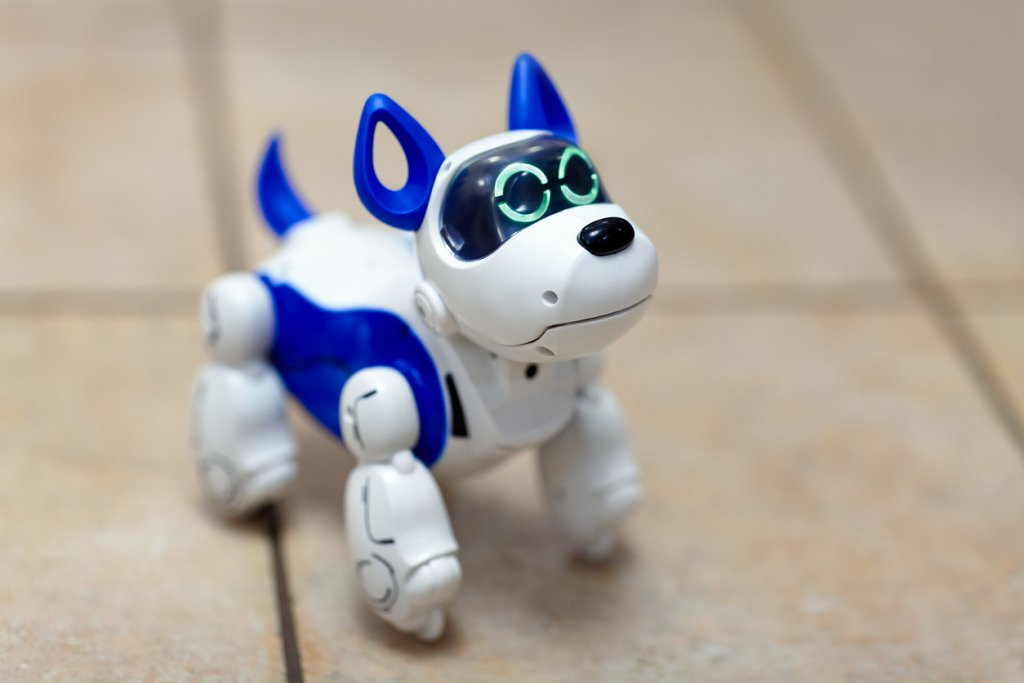 Electronic interactive toy dog puppy on a beige ceramic floor background of selective focus. High technology concept, pet of the future, electronic home.