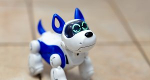 Electronic interactive toy dog puppy on a beige ceramic floor background of selective focus. High technology concept, pet of the future, electronic home.