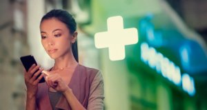 Woman in front of pharmacy, on mobile phone, during pandemic