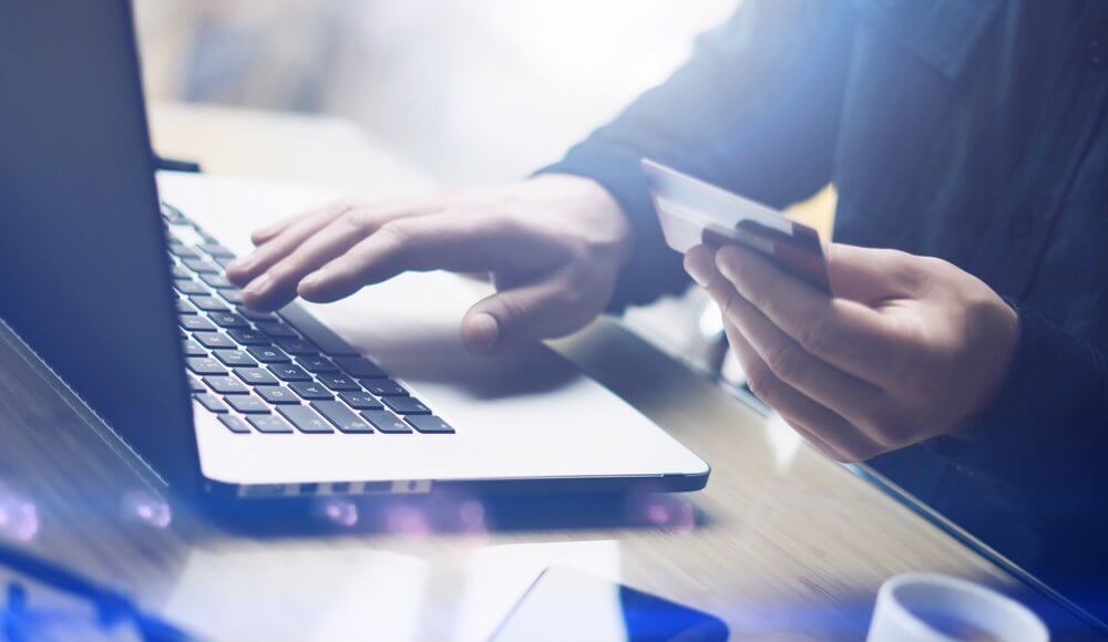 Business person holding credit card next to laptop