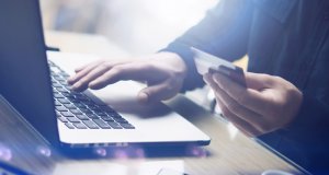 Business person holding credit card next to laptop