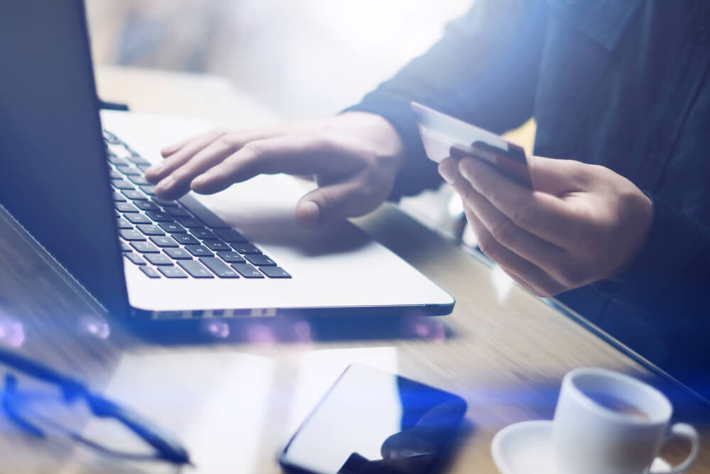 Business person holding credit card next to laptop