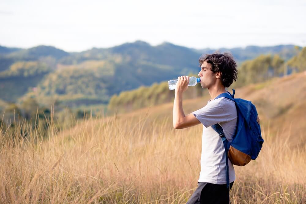 Man walking on Italian hillside, drinking water