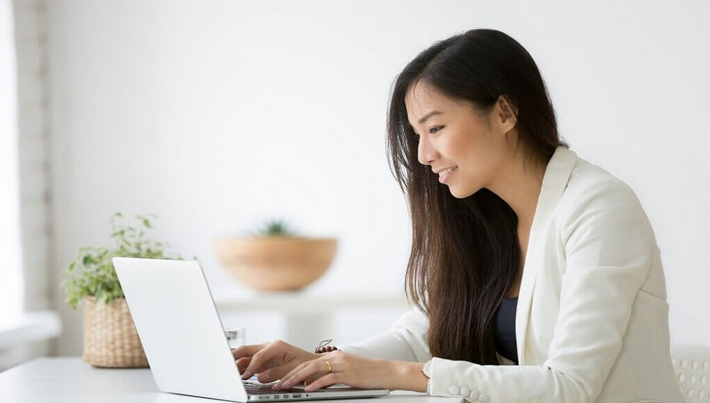 Aspiring CISO looking at laptop, young Asian business person