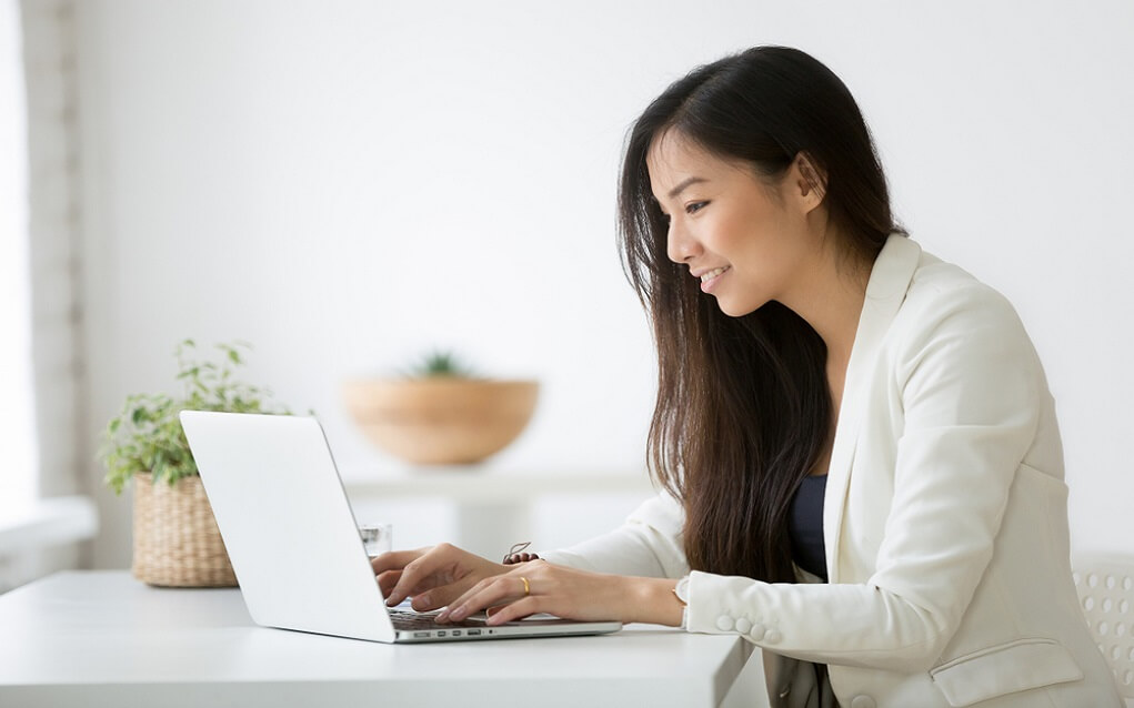 Aspiring CISO looking at laptop, young Asian business person