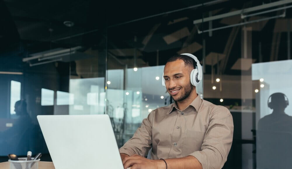 Young tech guy listening to music while working