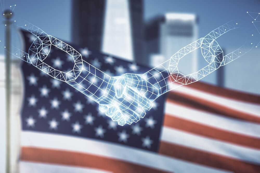 U.S.-led initiative vowing not to pay ransoms. Abstract, holographic image of two leaders shaking hands, with arms made out of block chain, infront of American flag.